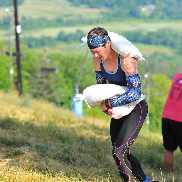 Strength & Speed Athlete Sam Oleskey carrying the double sandbag up a Spartan mountain.